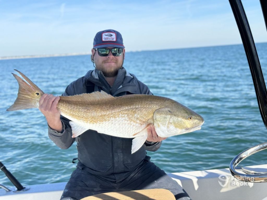 A man holding a big redfish while fishing on Hilton Head